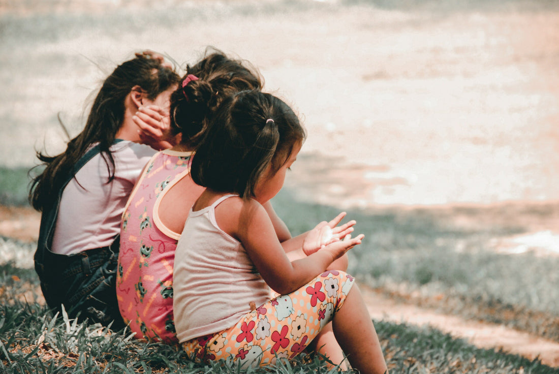Three young girls sitting on the grass together