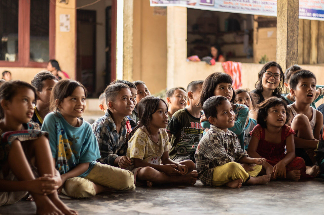 A group of children sitting on a floor listening to a speaker.