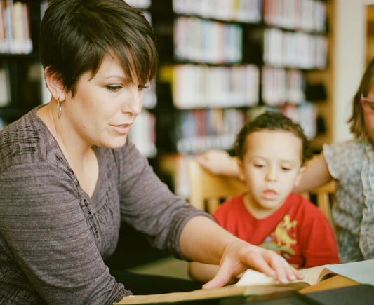 Teacher reading to a student in the library