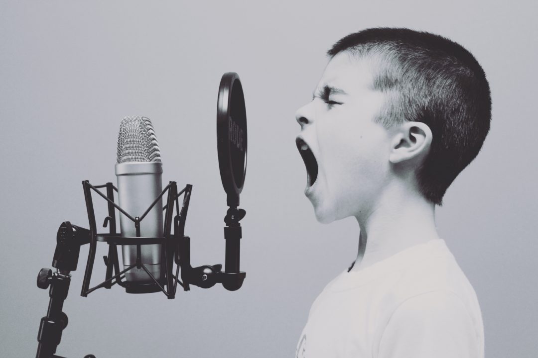 A young boy screaming into a microphone in black and white