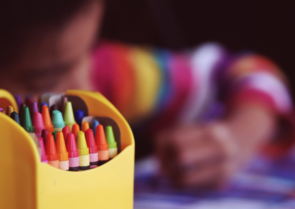 Box of crayons with child out of focus in background