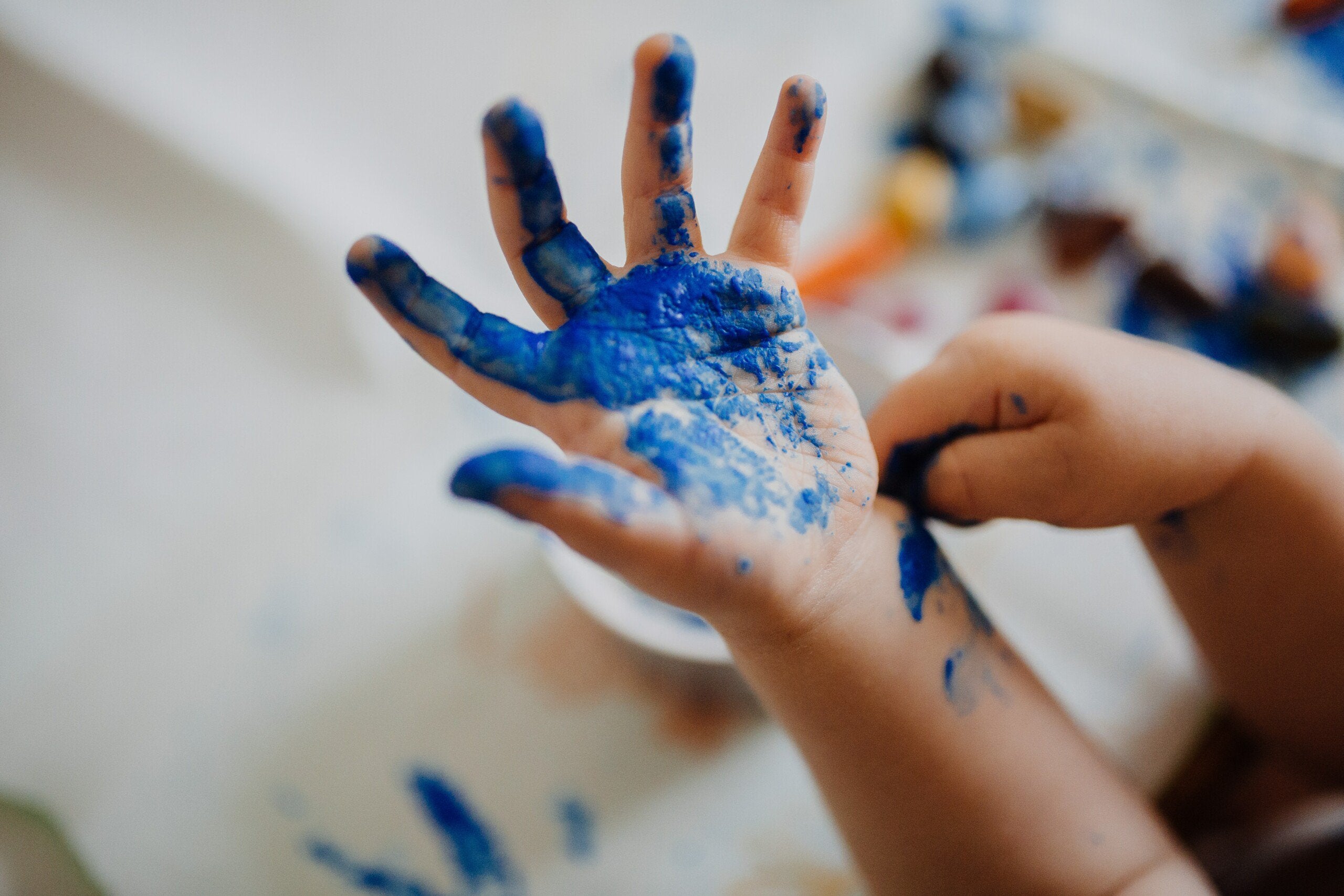 Hand of a child covered in blue paint